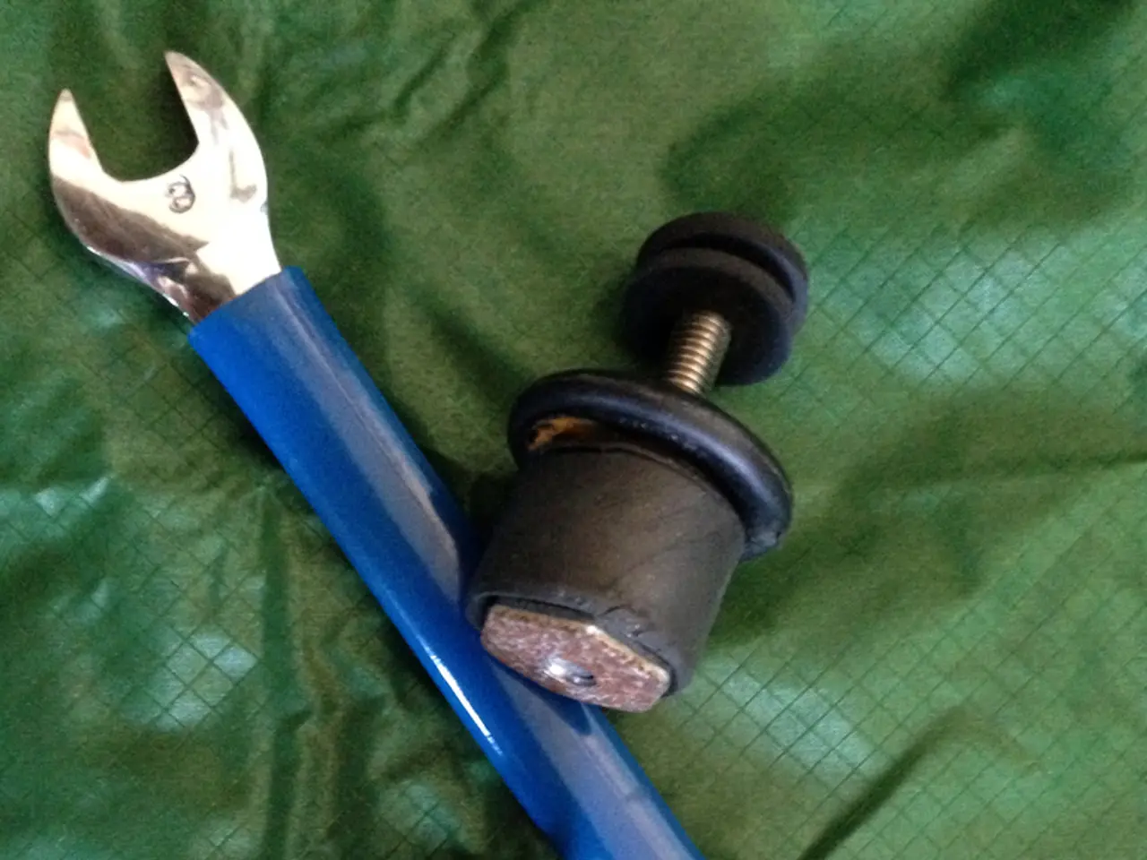 In this image we can see a wrench and some objects placed on the surface.