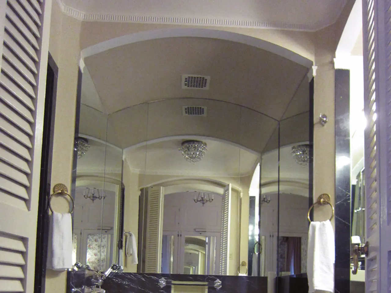 In this image, we can see a mirror in between towels. There is a toilet seat in the bottom left of...