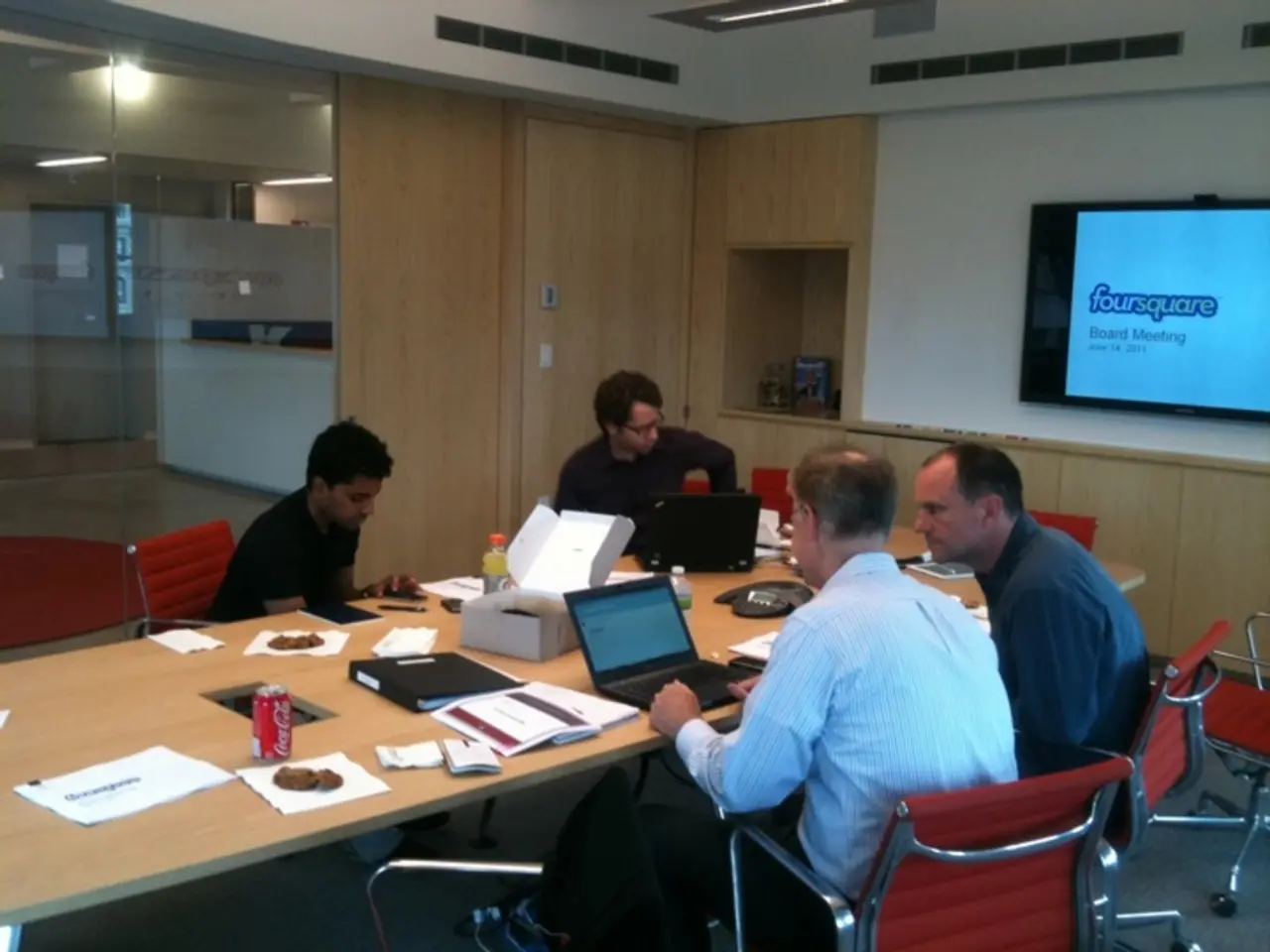 In this image there are group of people, they are sitting on the chairs around the table and there...