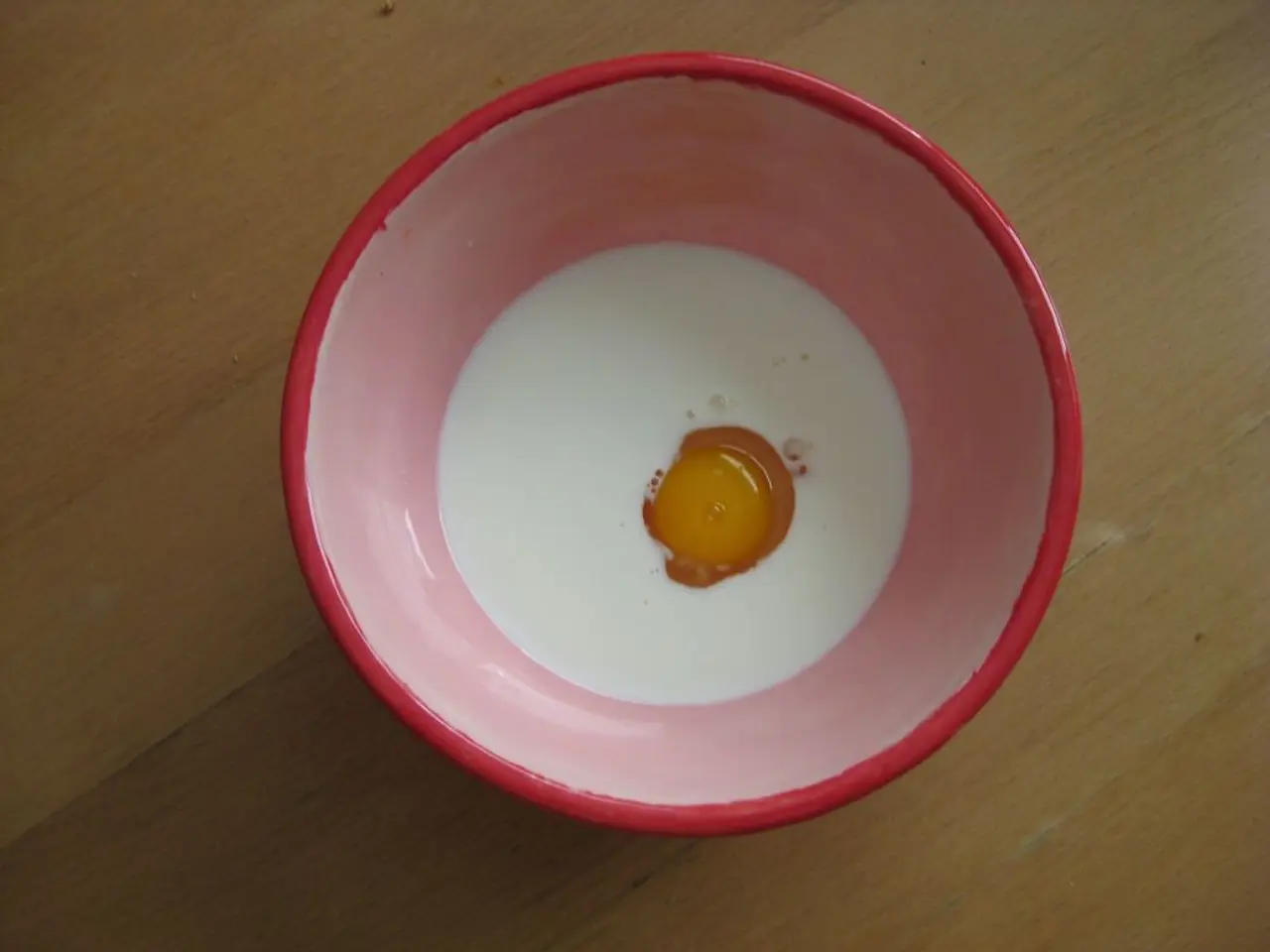 In this picture we can see a bowl, there is some milk and yolk present in this bowl, at the bottom...