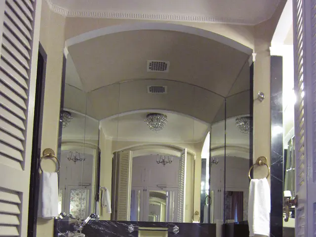 In this image, we can see a mirror in between towels. There is a toilet seat in the bottom left of...