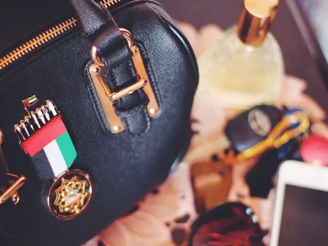 There is a handbag in the left hand side. There is a flag. sunglasses and some objects on the...