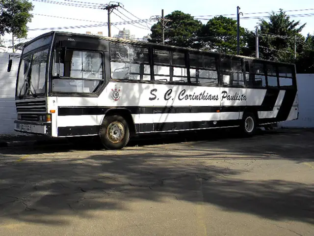 In this picture we can see a bus parked on the road and behind the road there is a wall, electric...