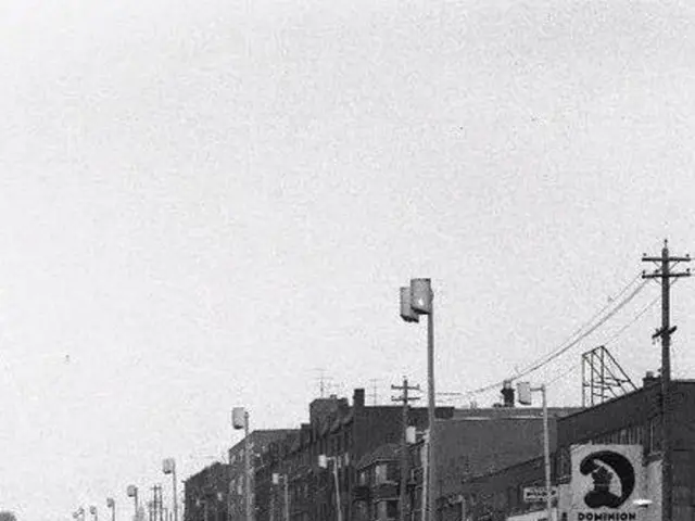 In the picture we can see black and white image of the buildings and near it we can see some poles...