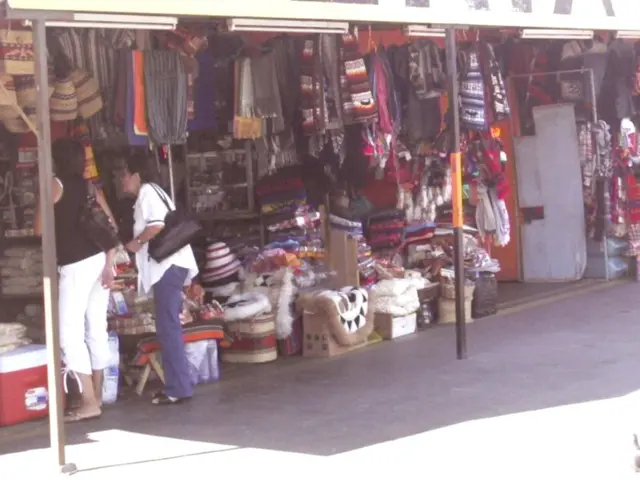 In this picture there are stalls in the image and there are two ladies on the left side of the...