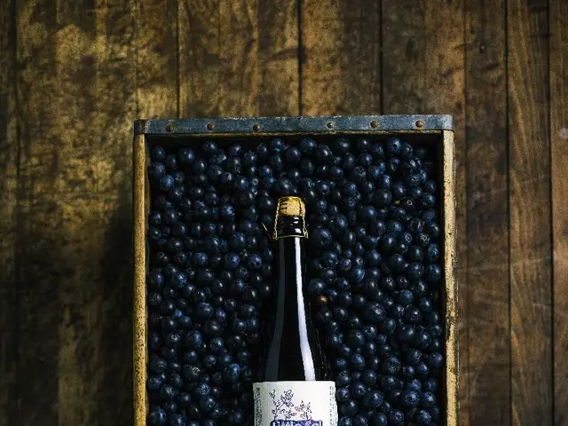 In this image we can see a container placed on the surface containing some berries and a bottle in...