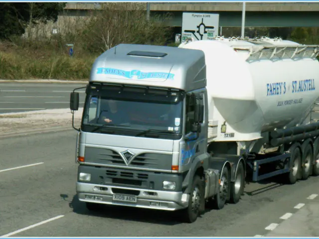 In this image there is a truck passing on the road, inside the truck there is a driver, on the...