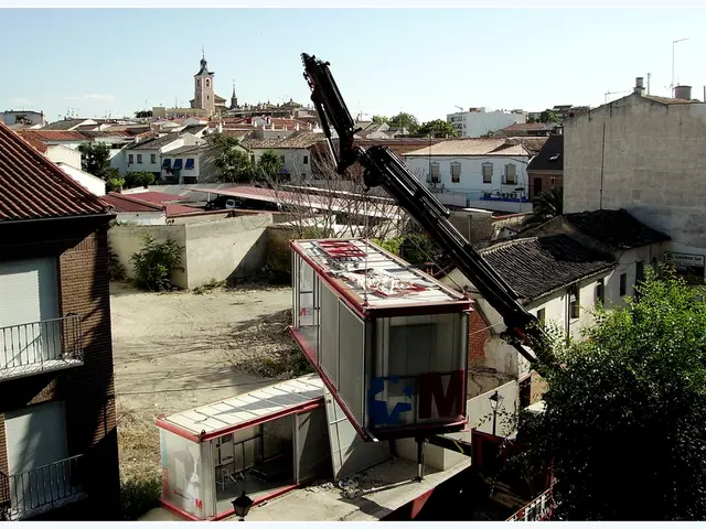 In this image we can see there are so many buildings and trees, there is a crane holding container.